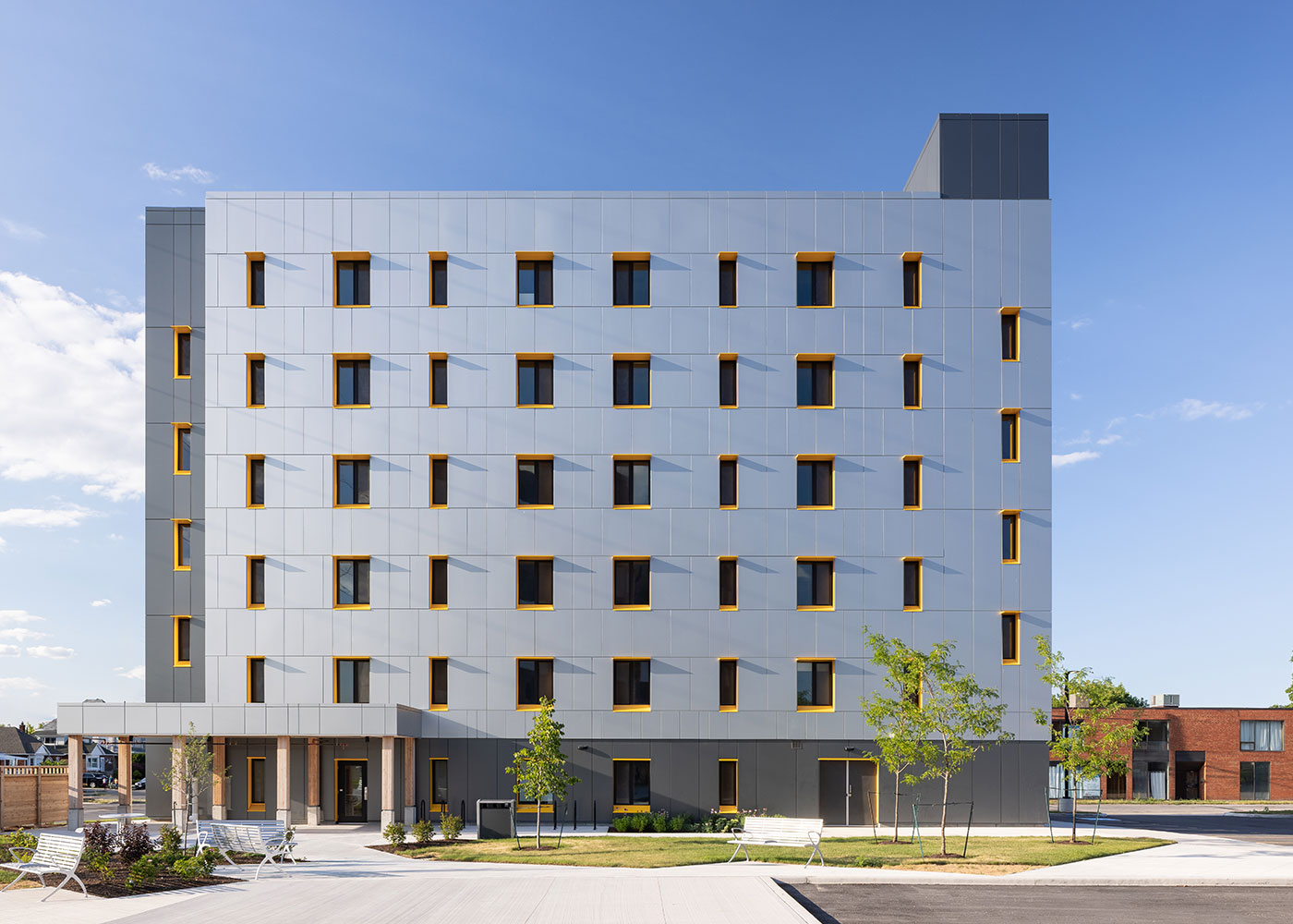 Photograph of the completed six-storey housing building with matching facade and yellow window frames
