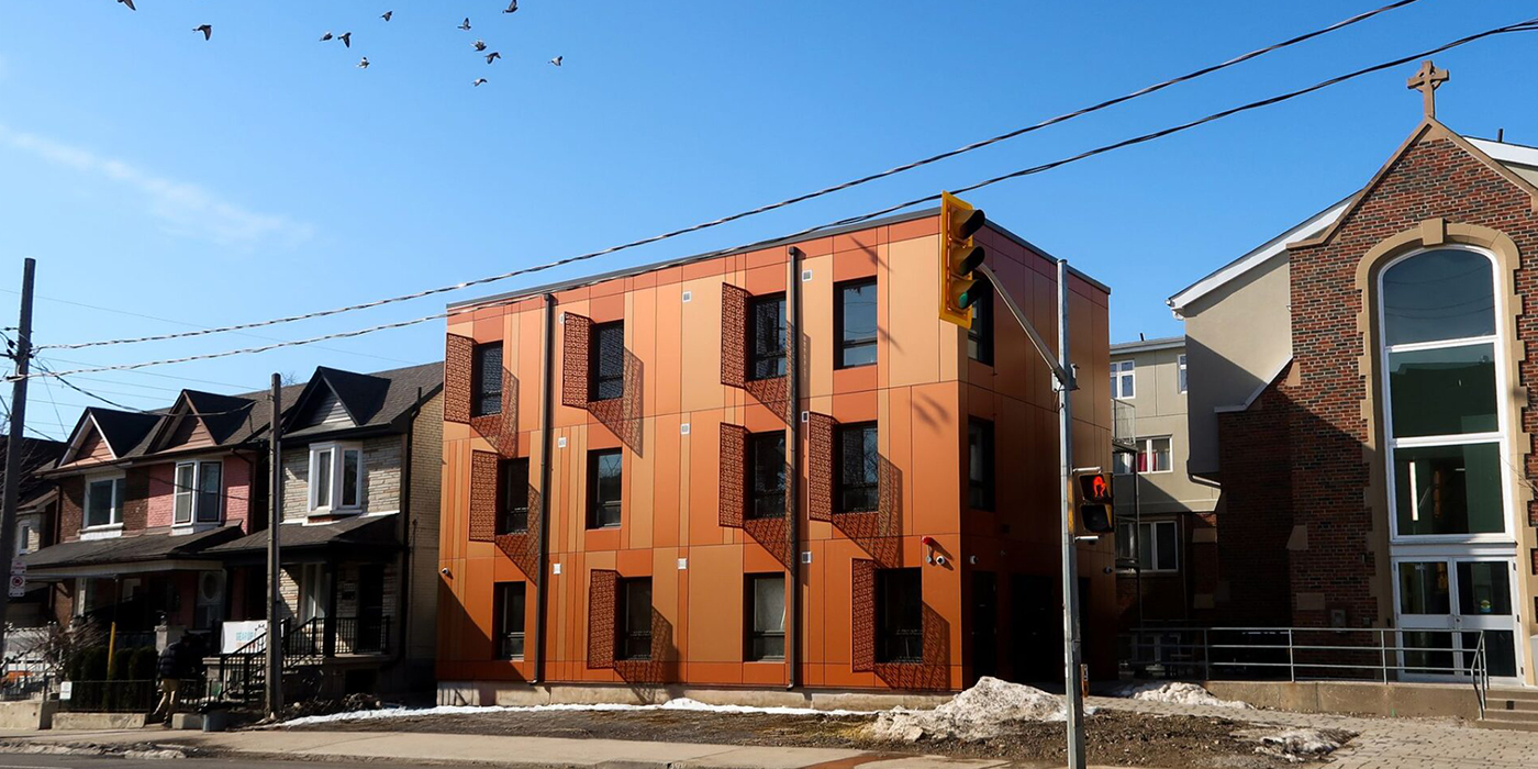 Completed supportive housing building seen from the street beside the church