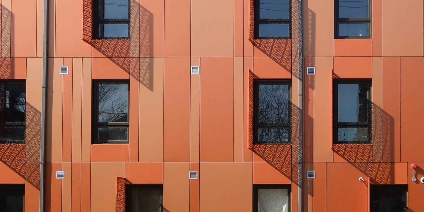 Close view of windows and patterned shadows across the orange façade