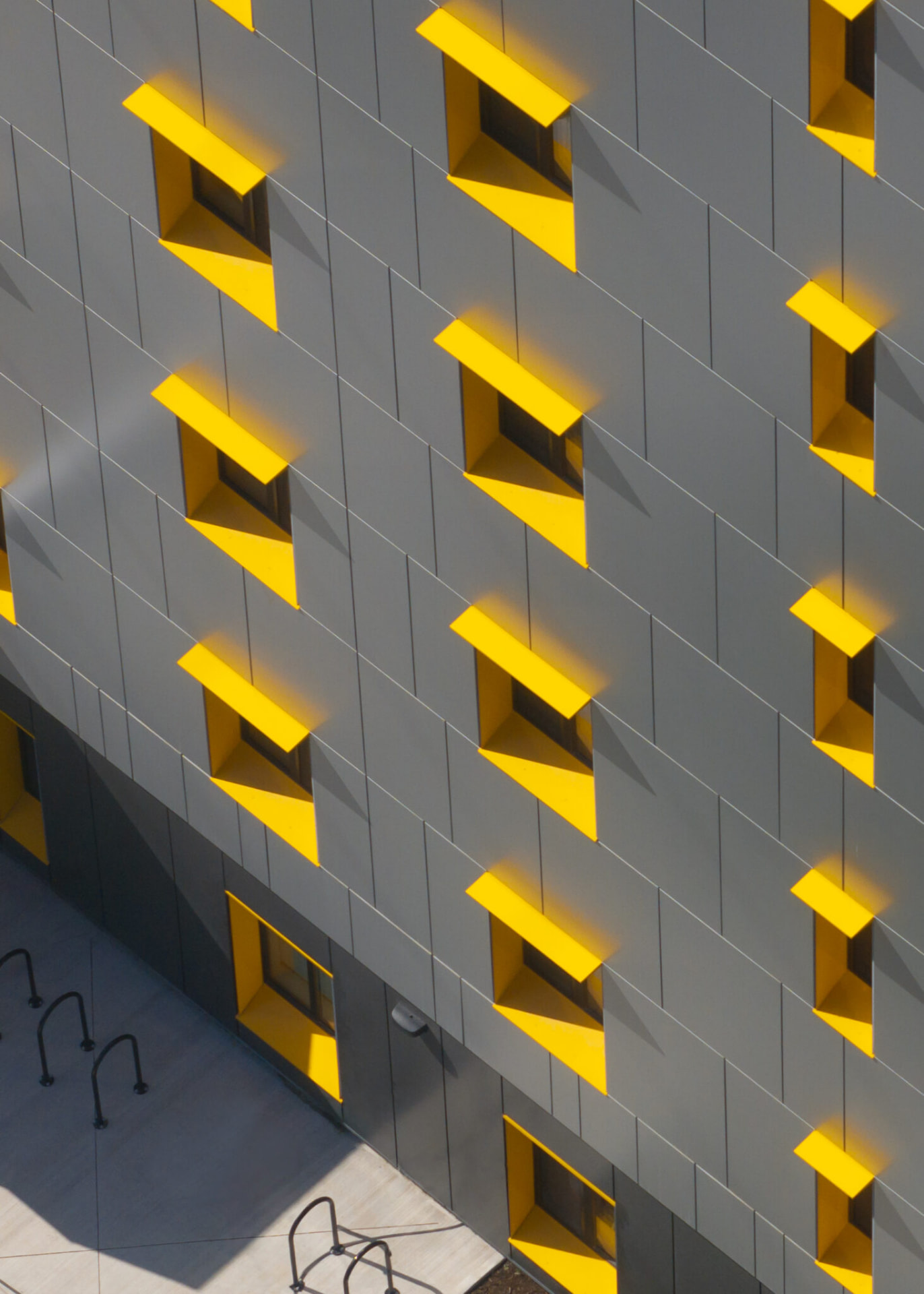 Close view of the grey façade panels and yellow window reveals