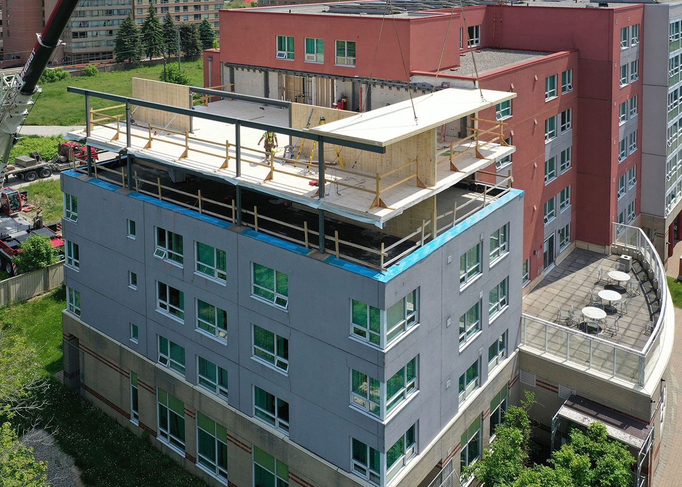 Aerial view of prefabricated timber panels being placed above the existing building