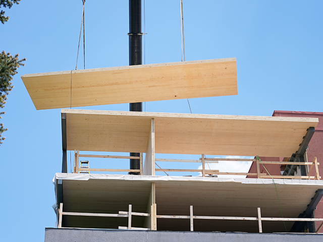 Prefabricated mass timber panel being lowered into place during construction