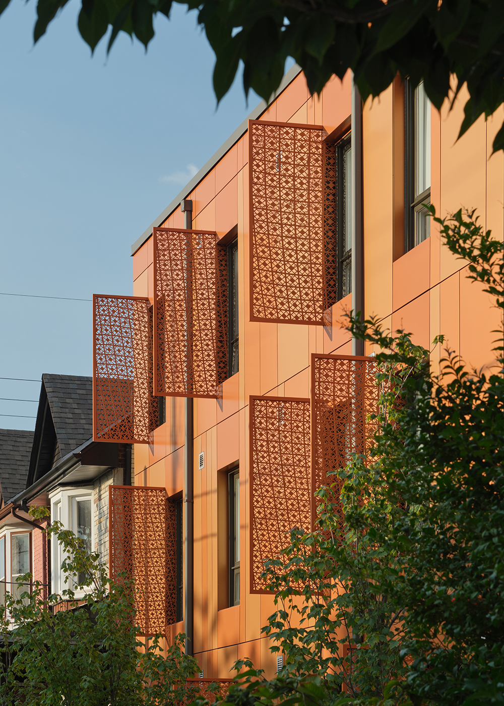 Angled view of the orange façade and patterned window screens